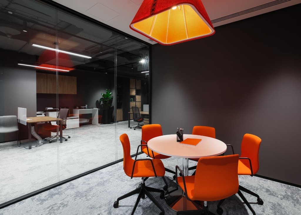 Glass-partitioned meeting nook with orange pendant light