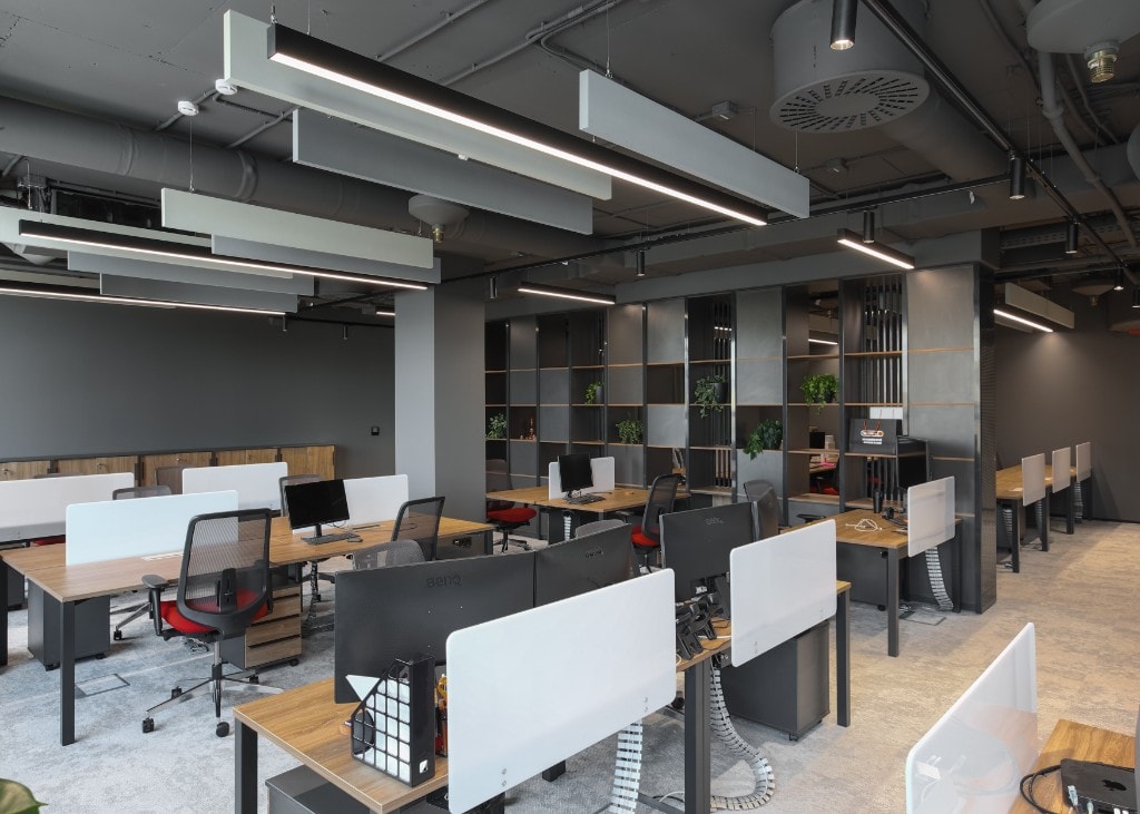 Open-plan workspace with dark ceiling and red accent chairs