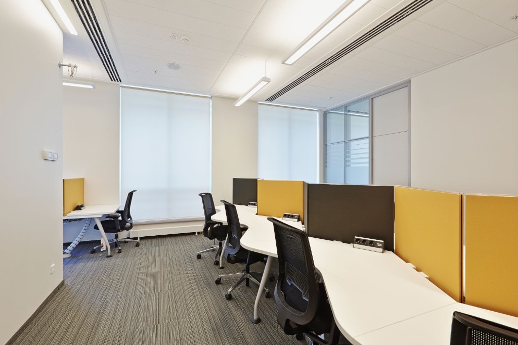 Workstations with yellow and grey dividers near window blinds
