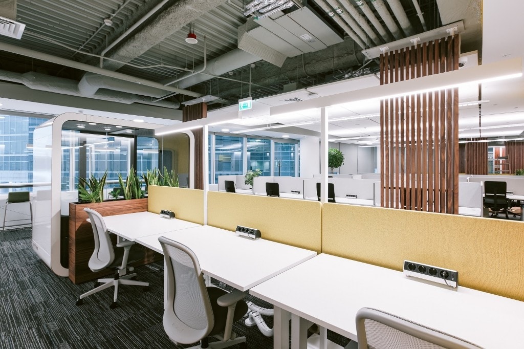 Open workspace with yellow privacy screens and acoustic phone pod
