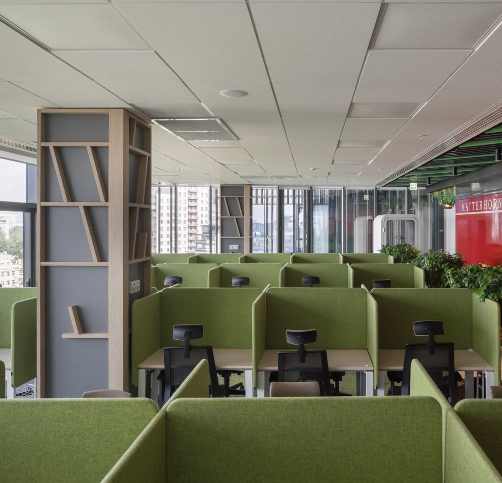 Open workspace with green acoustic screens and geometric wood column