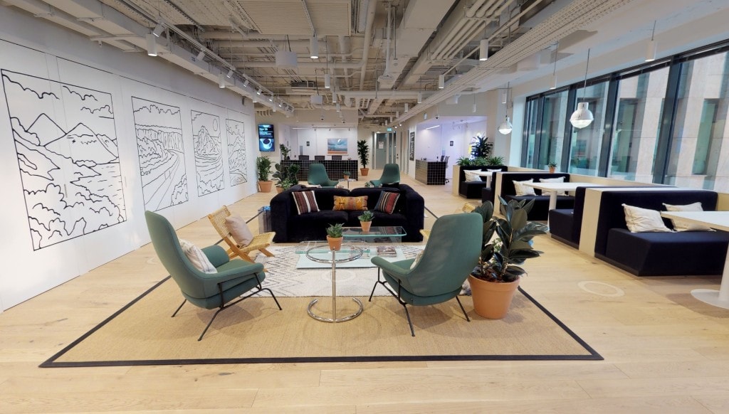 Collaborative lounge with teal armchairs and landscape mural partitions