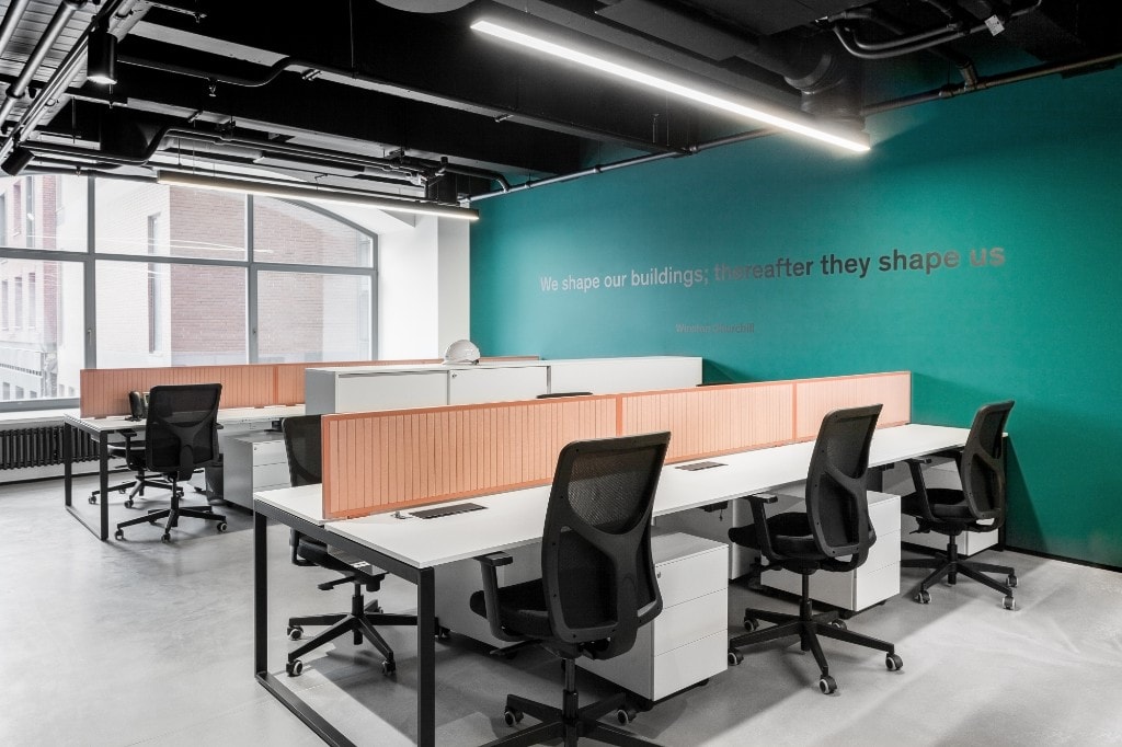 Open-plan office with workstations and teal accent wall